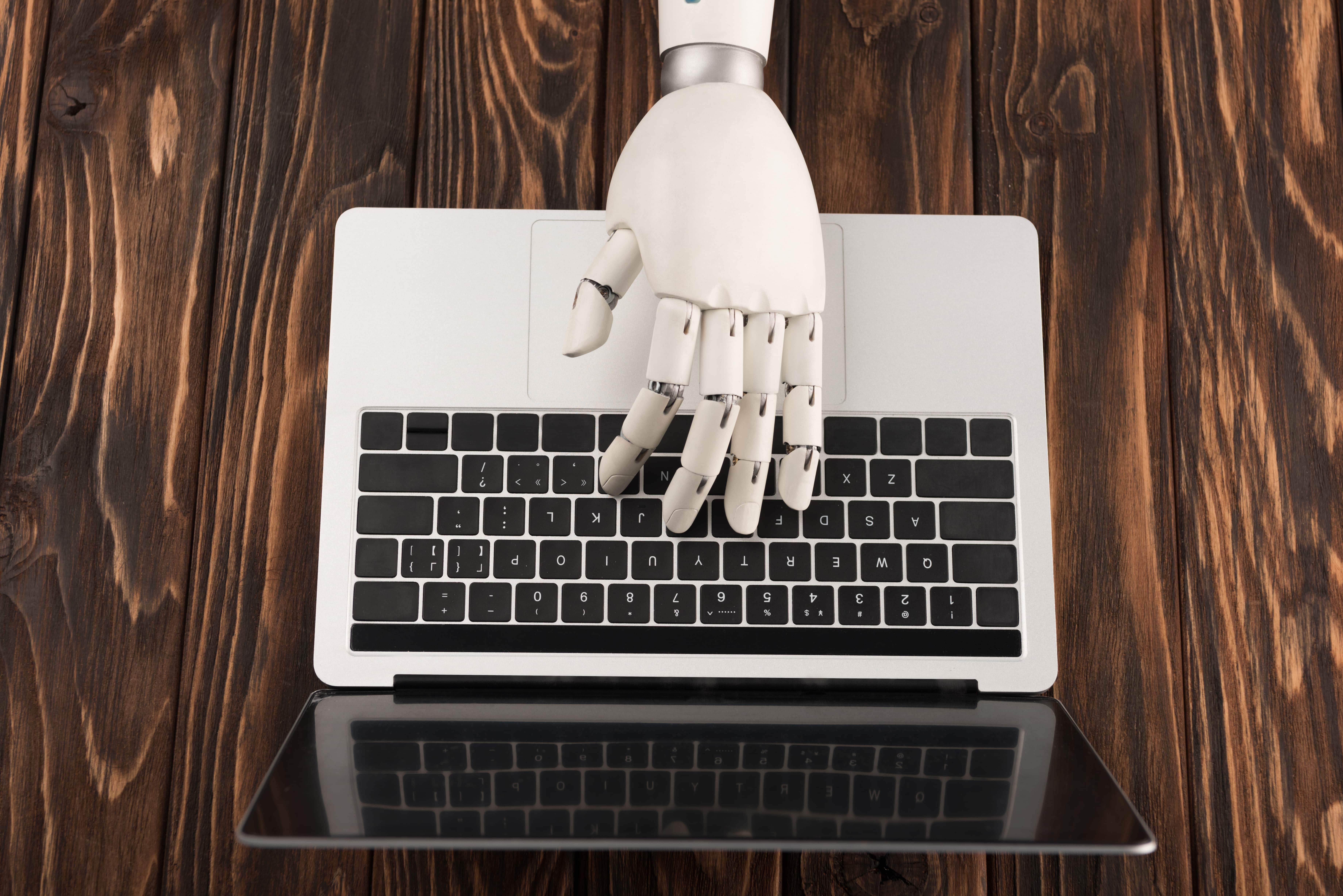 cropped-shot-of-robot-working-with-laptop-on-wooden